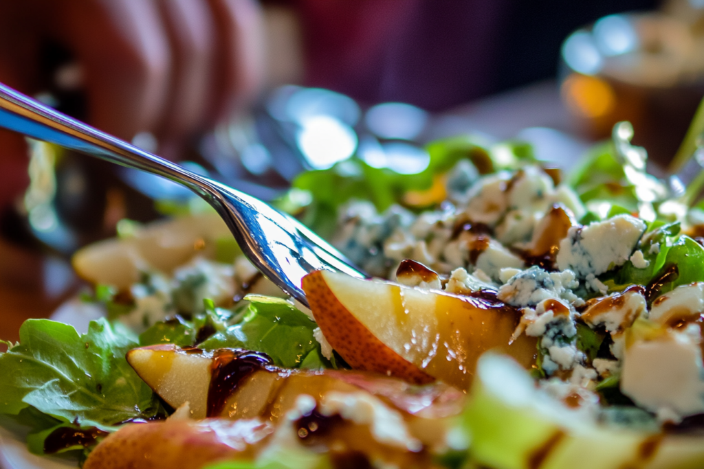 Pear and Blue Cheese Salad being tossed with vinaigrette.